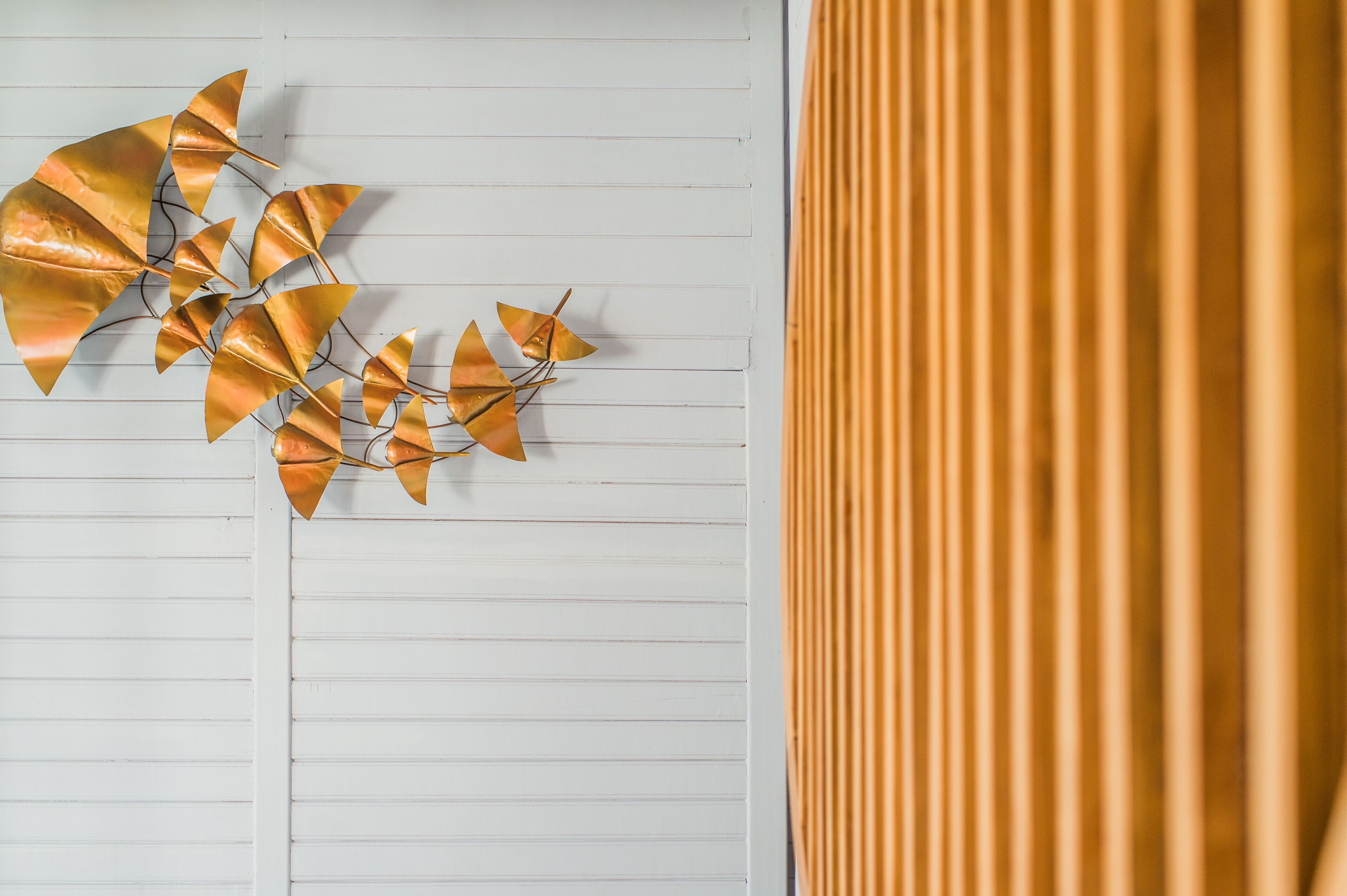 A wall with horizontal lines and a decorative metal leaf arrangement.