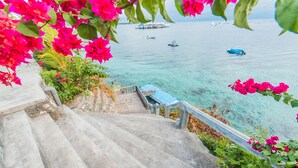Un escalier en béton mène à une jetée d’où l’on peut admirer la mer et les bateaux.
