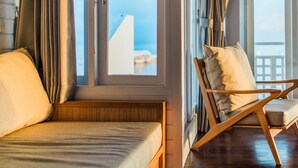 Une pièce avec un lit, une chaise en bois et une fenêtre avec des rideaux.