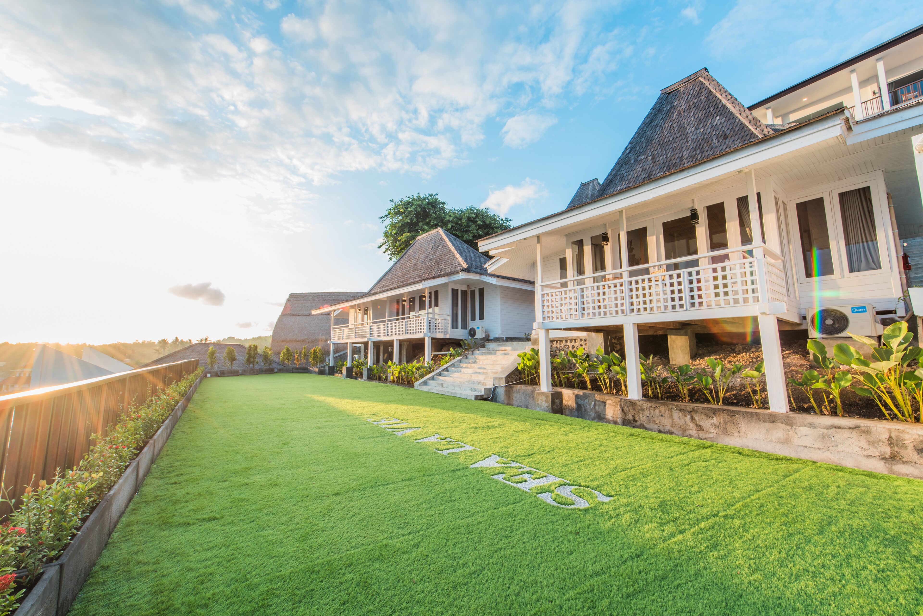 A residential property with a well-maintained lawn, a covered porch, and a staircase leading to the entrance.