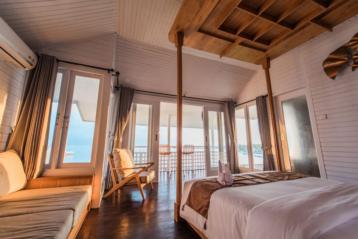 Ett rum med en säng, en soffa och en balkong med utsikt över havet.