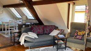A cozy loft bedroom with a sloped ceiling, a grey sofa, a wicker armchair, a small table, and a skylight. - Vacation cottage Alte Kirchgasse (Zell (Mosel))