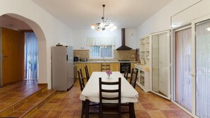 Cocina compacta con comedor, que incluye una isla central, horno empotrado y un ventanal grande.