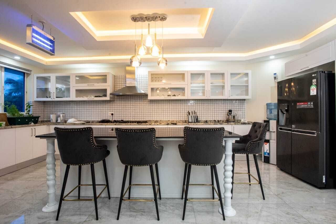 Una cocina moderna con una isla central, taburetes de bar y un refrigerador negro.
