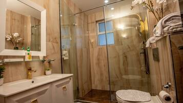 Un baño moderno con cabina de ducha de vidrio, tocador con espejo y retrete.