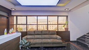 Zona de recepción con un sofá, una planta en maceta y una ventana con vistas a la ciudad.