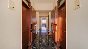 Un pasillo de hotel con puertas de madera, suelo de mármol y un extintor en la pared.