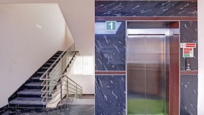 Un ascensor moderno con pared de mármol, una escalera con barandillas de cristal y un letrero que dice 'No Smoking'.