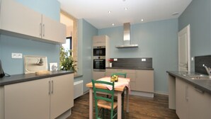 Una cocina moderna con paredes azul claro, suelo de madera y un comedor con mesa y sillas.