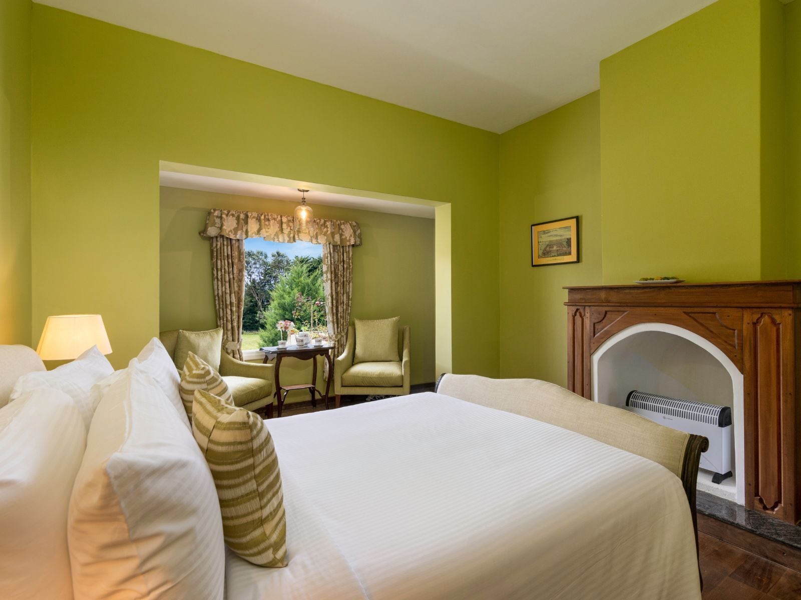 A room with a bed, a table with chairs, a fireplace, and a window with curtains.