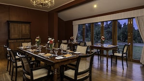 A dining area with a long table set for multiple guests, surrounded by chairs with woven seats.
