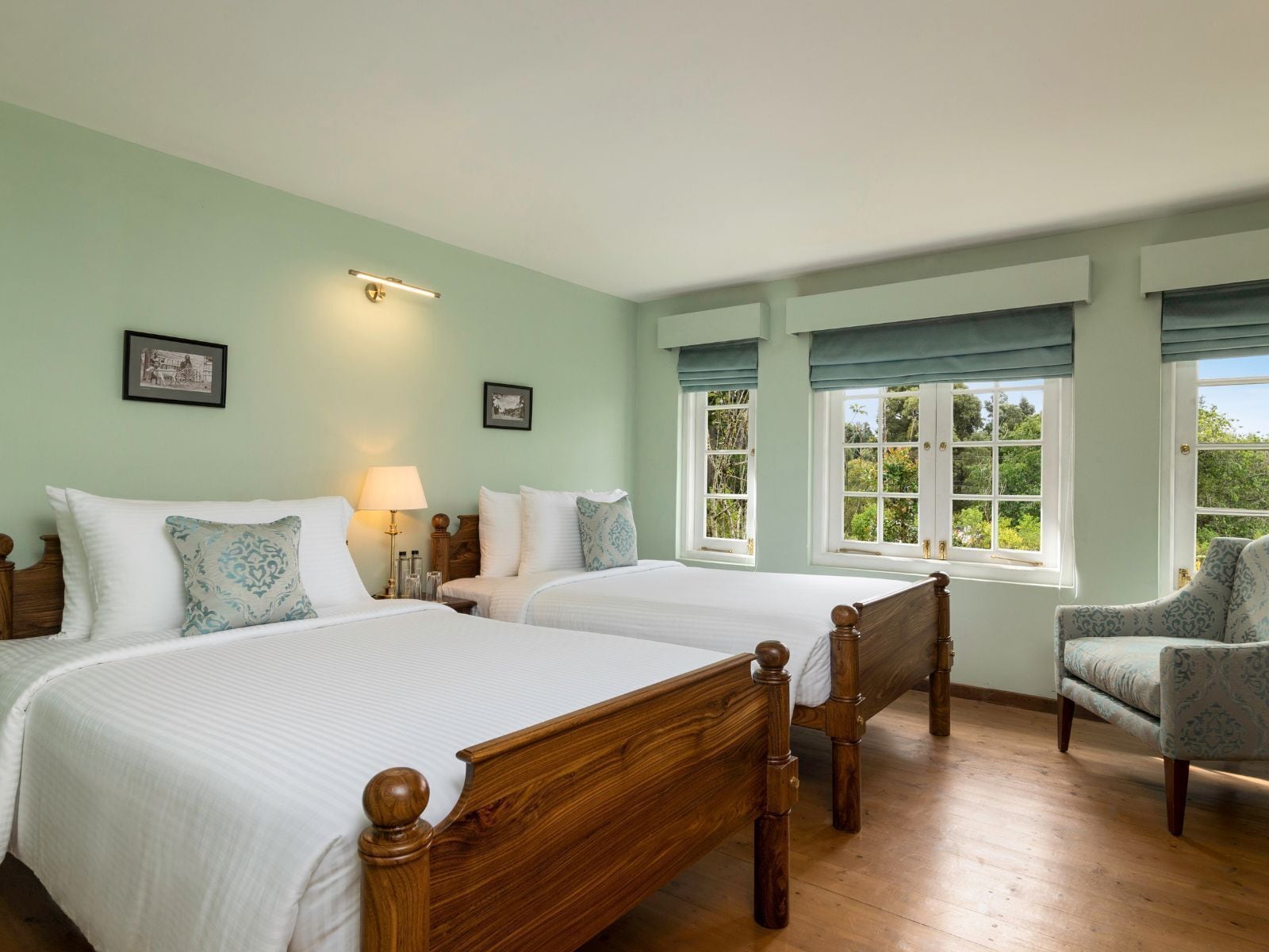 A bedroom with two wooden beds, a nightstand, a lamp, and a chair.