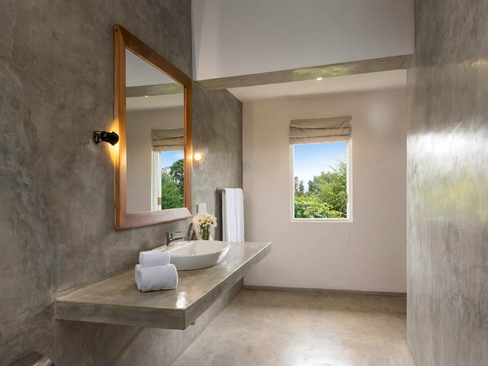 Un bany modern amb un mirall gran, un lavabo integrat i una finestra que ofereix vista a vegetació.