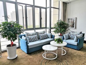 Ein modernes Wohnzimmer mit zwei Sofas, einem Couchtisch und Topfpflanzen.