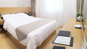 A hotel room with a large bed, a wooden nightstand, a desk with a chair, and a window with curtains. - Greentree Inn Shanghai Jinshan District Wanda Plaza Longhao Road Express Hotel (Shanghai)