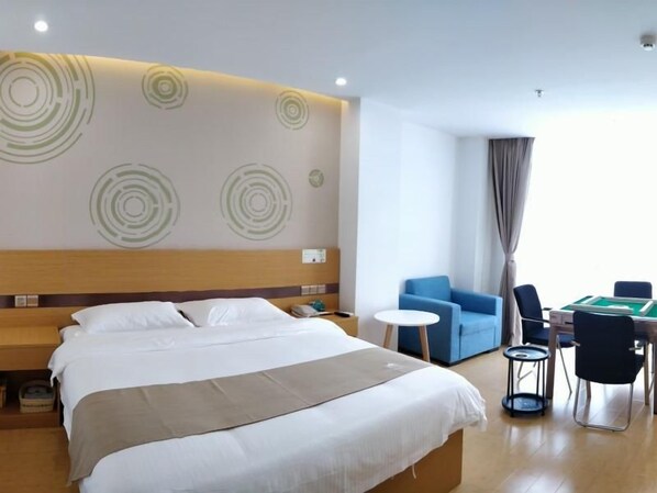 Ein Hotelzimmer mit einem großen Bett, einem kleinen runden Tisch, einem blauen Sessel und einem Billardtisch.