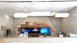 A modern reception area with a counter, three monitors, a digital kiosk, and a decorative wall. - Greentree Inn Shanghai Jinshan District Wanda Plaza Longhao Road Express Hotel (Shanghai)