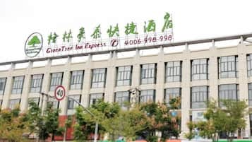 A building with a sign for GreenTree Inn Express, featuring a logo with a tree and the name in English and Chinese.