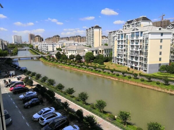 A river running alongside a row of modern apartment buildings with a parking lot in the foreground. - Greentree Inn Shanghai Jinshan District Wanda Plaza Longhao Road Express Hotel (Shanghai)