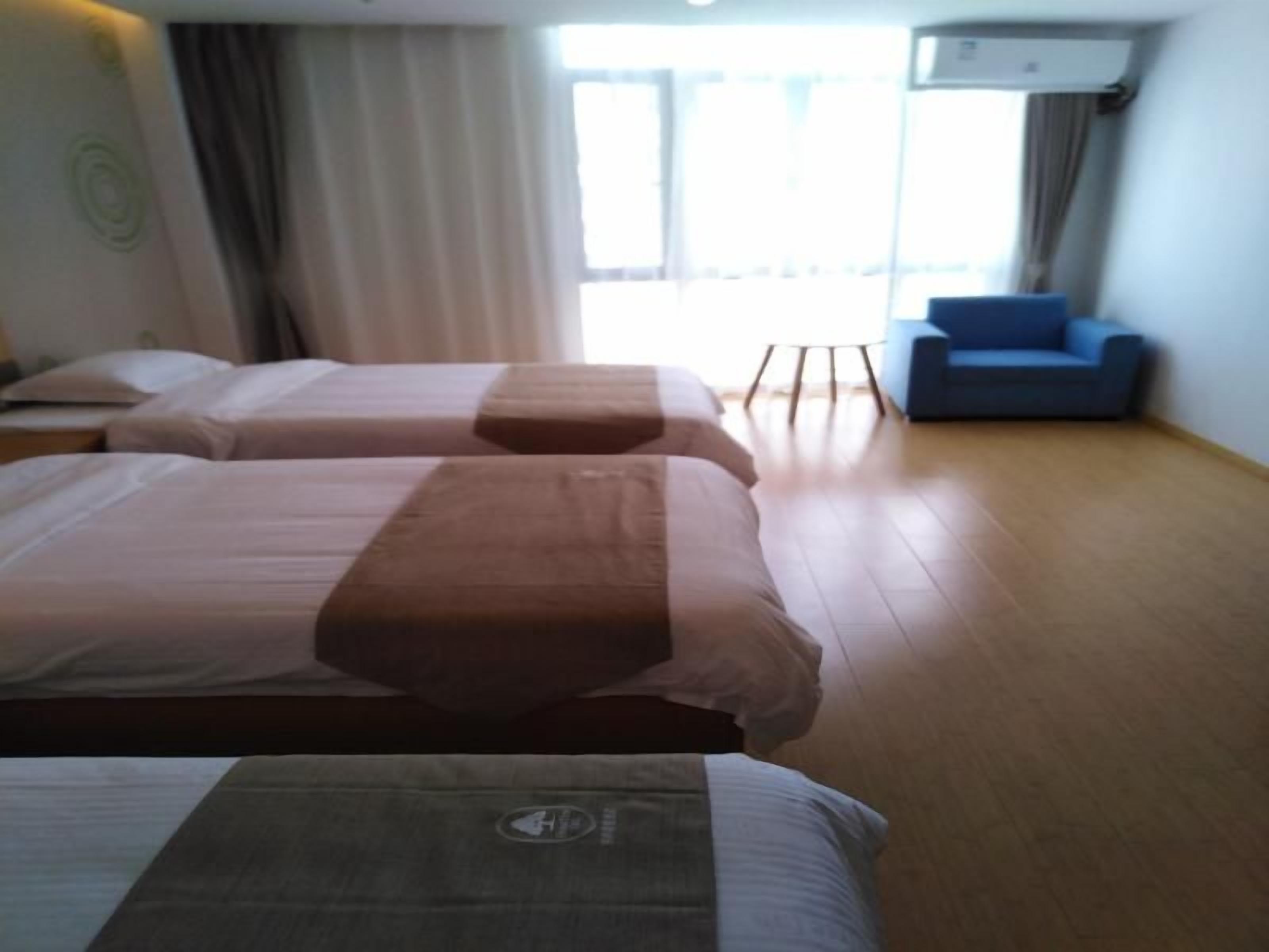 A hotel room with two beds, a blue sofa, and a large window.