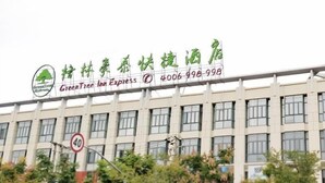 A building with a sign for GreenTree Inn Express, featuring a logo with a tree and the name in English and Chinese. - Greentree Inn Shanghai Jinshan District Wanda Plaza Longhao Road Express Hotel (Shanghai)