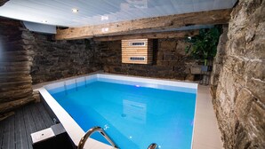 Una piscina interior con paredes de piedra y cubierta de madera.