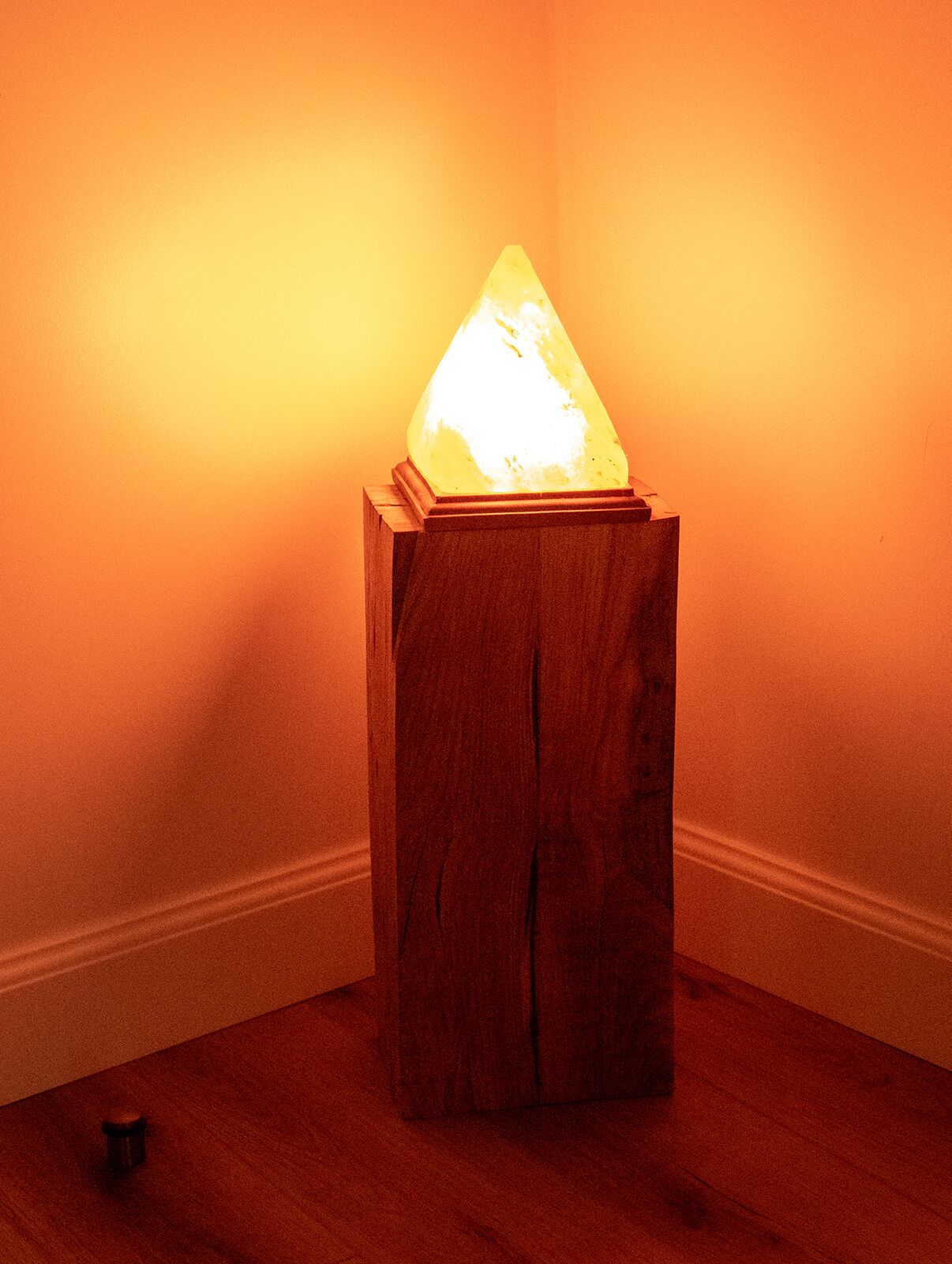 Una mesa de madera con un cristal brillante encima, colocada frente a una pared lisa.