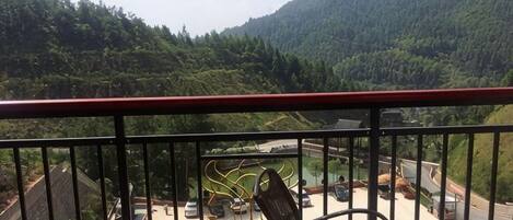 A balcony with a view of a parking area and a mountainous landscape.