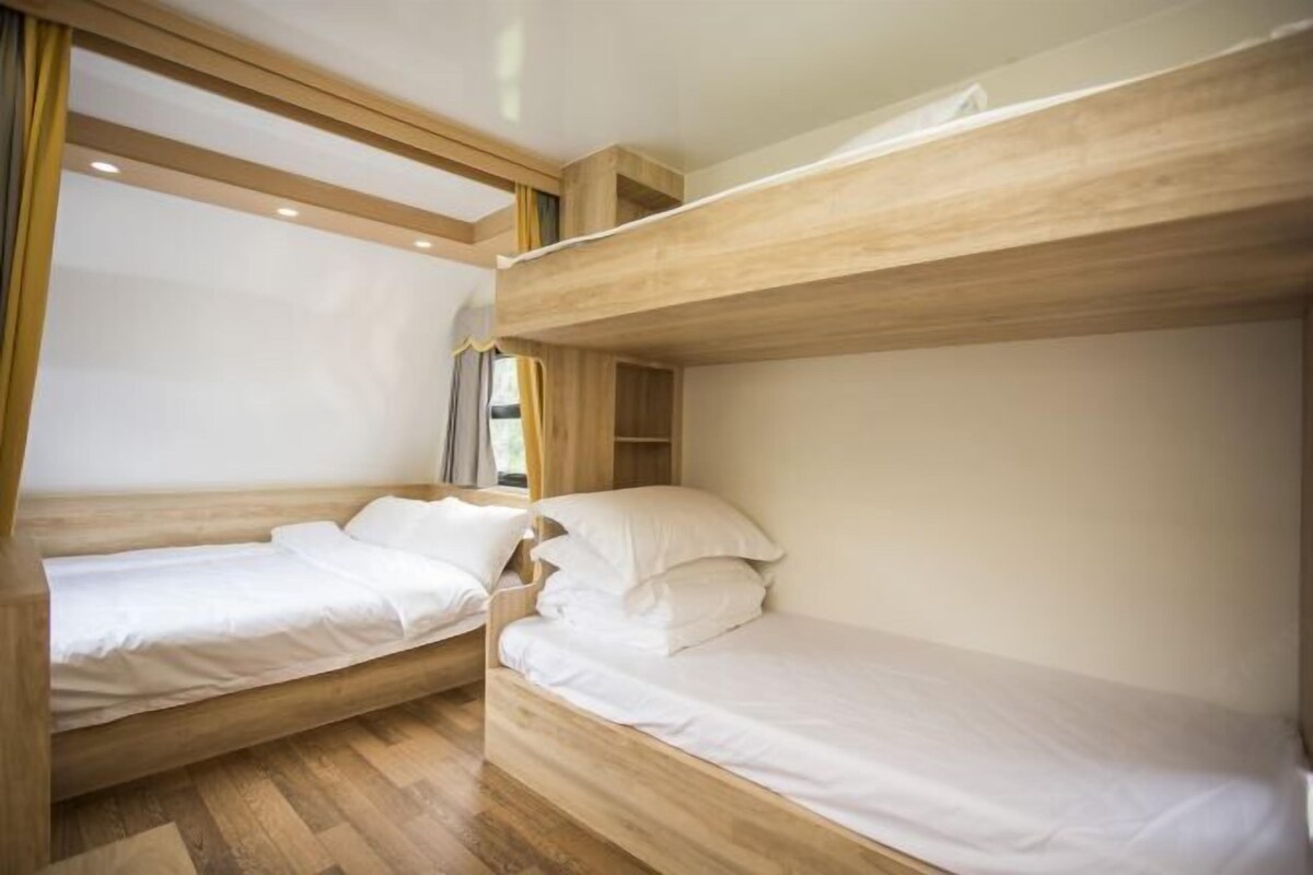 Dormitorio con literas, cabeceros de madera y ropa de cama blanca.