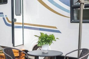 Una pequeña mesa con una planta en maceta, una silla y una ventana con cortinas.
