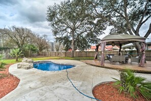Un jardin avec une piscine, une terrasse en bois et un kiosque.