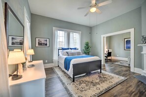 Une chambre à coucher avec un lit, des lampes de chevet, un miroir et une fenêtre avec des rideaux.