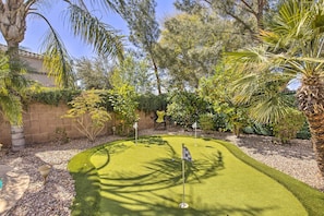 Un parcours de minigolf avec un green d’entraînement, entouré de palmiers et de divers arbustes.