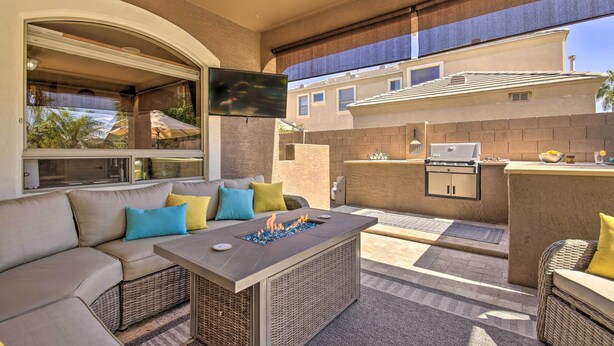 An outdoor living area with a sofa, fire pit, grill, and TV. - Family Gem in Phoenix w/ Saltwater Pool & Theater (Gilbert)
