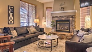 A living room with a stone fireplace, leather sofas, and a round coffee table. - Family Gem in Phoenix w/ Saltwater Pool & Theater (Gilbert)