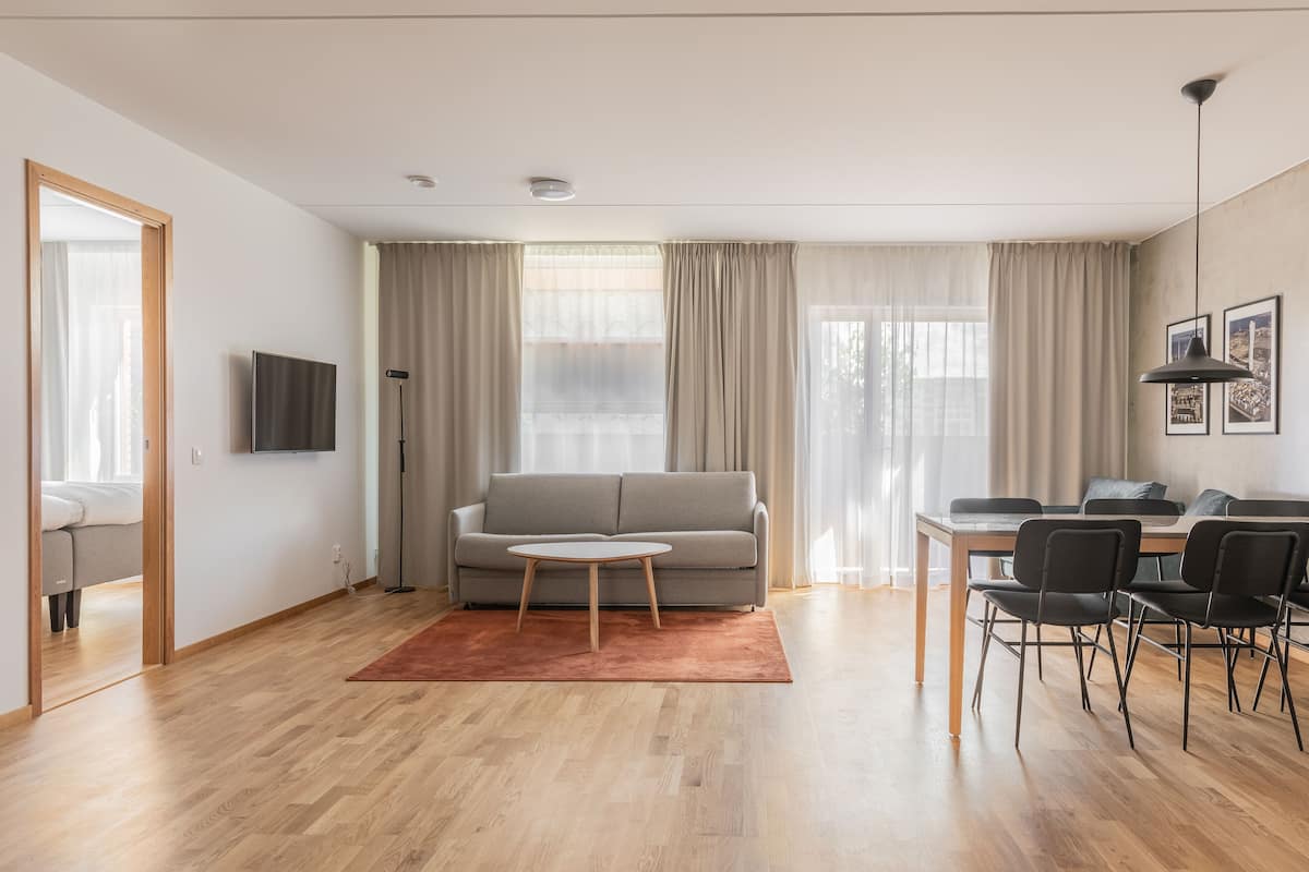 Een moderne woonkamer met een bank, salontafel en een eethoek met stoelen.