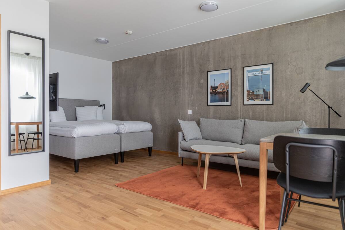Een moderne woonkamer met twee grijze banken, een klein rond tafeltje en een zwarte stoel.