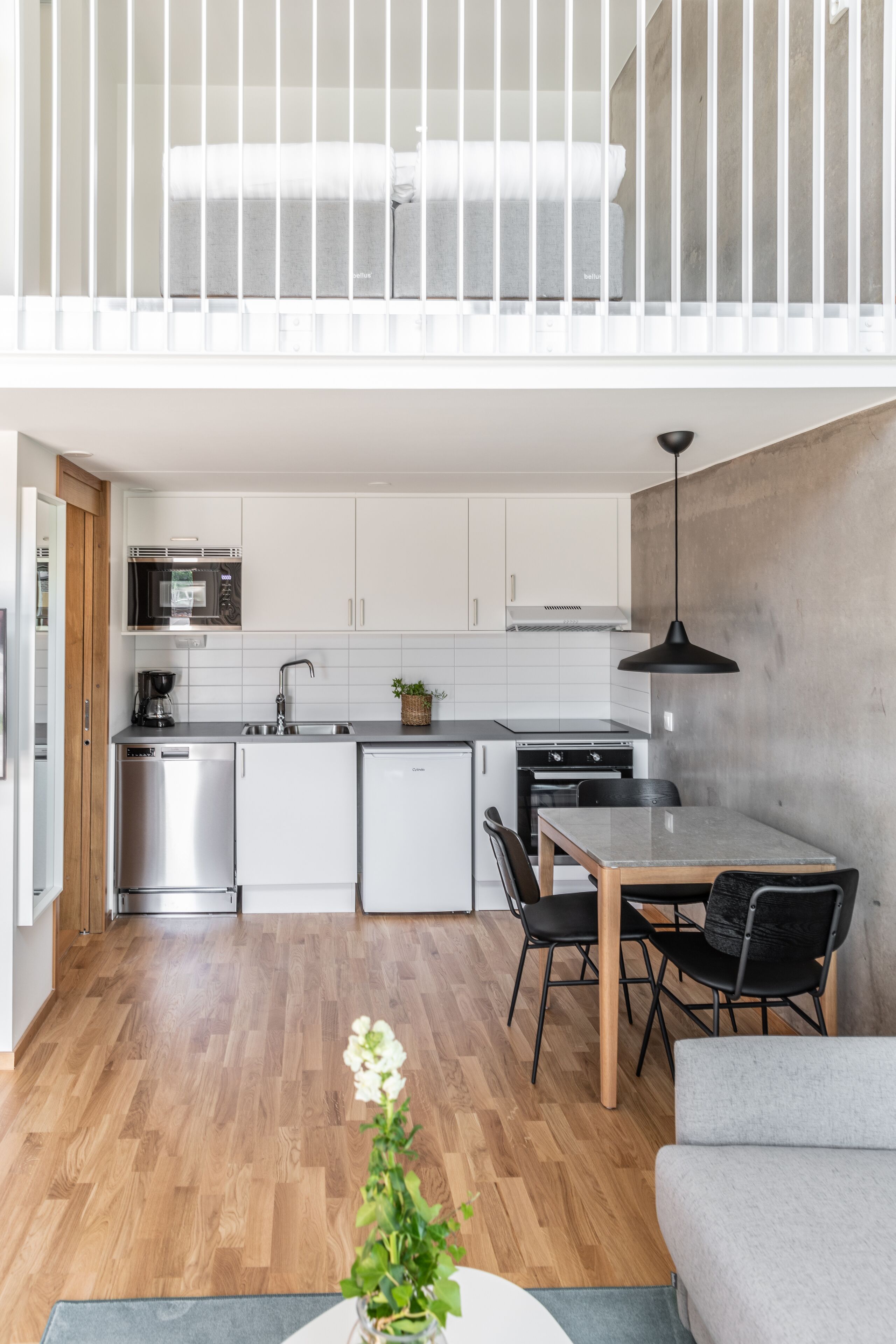 Une cuisine moderne avec des meubles blancs, des appareils en acier inoxydable et un coin repas comprenant une table et des chaises.