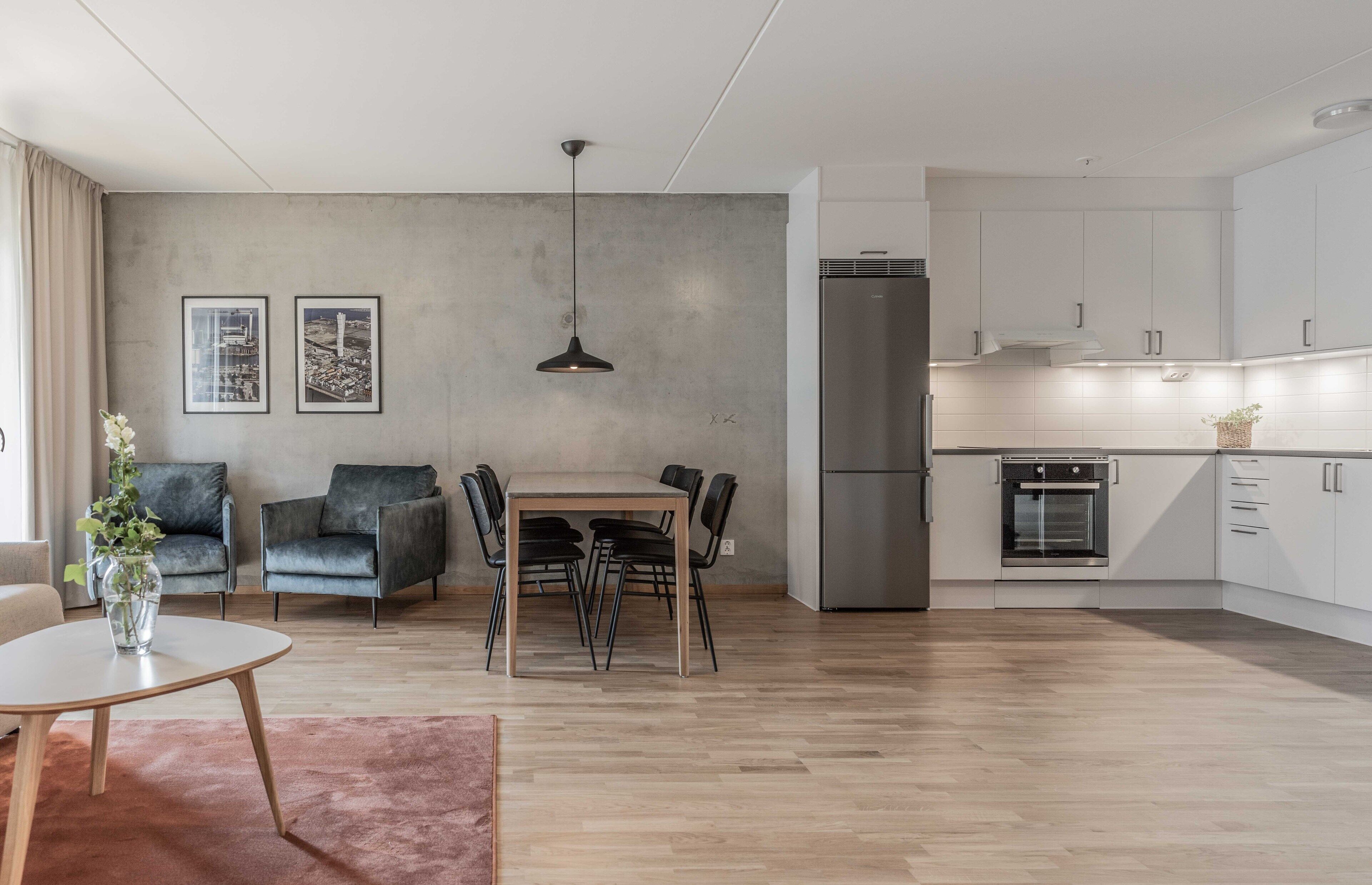 A modern living room with a dining area, a kitchen, and a large window.