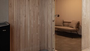 Een houten deur die leidt naar een kamer met een bank en een stoel.