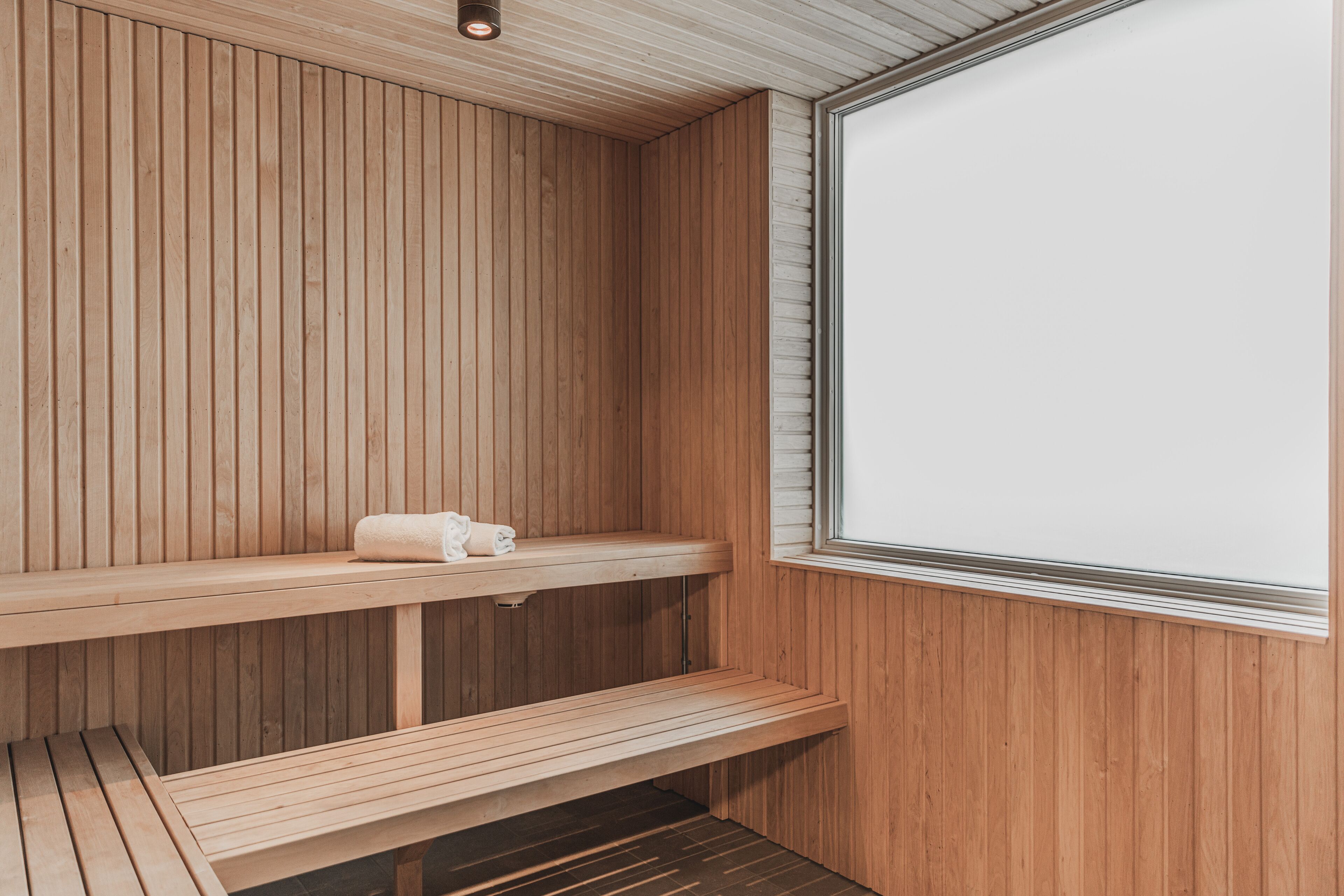 Sala de sauna com bancos de madeira e uma janela grande.