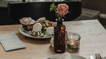 A dining table with plates of food, a vase with a flower, and a candle.
