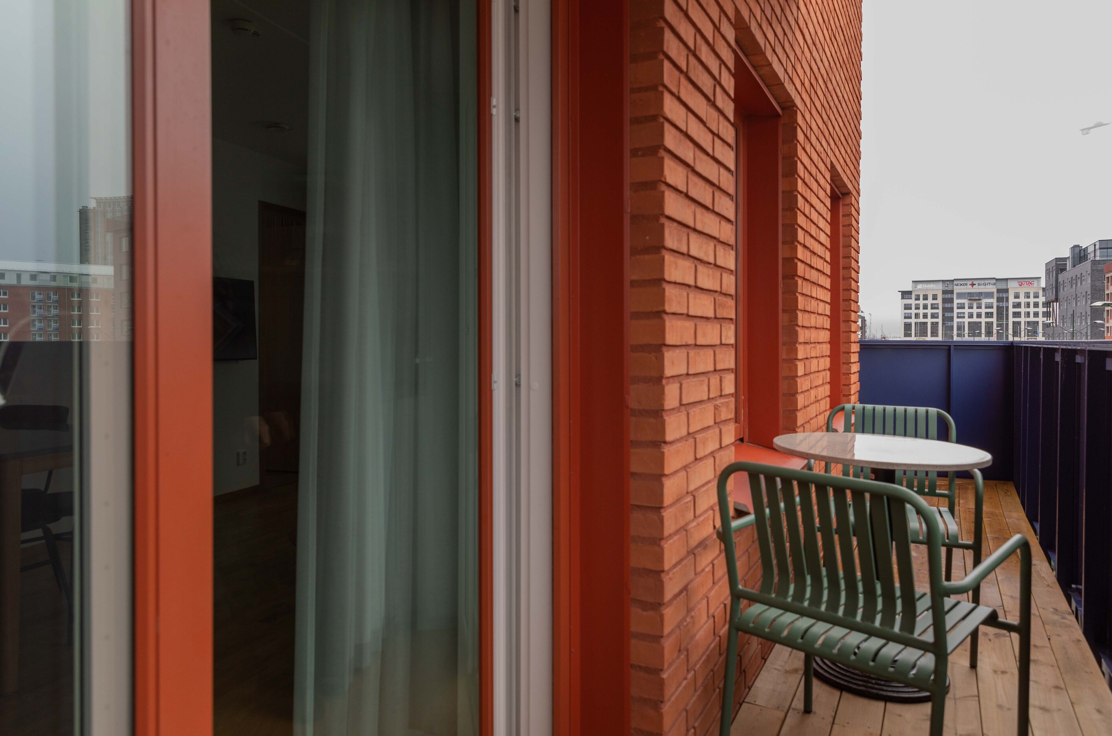 A balcony with a brick wall, a glass door, and a table with chairs.