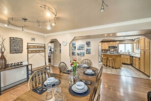 A dining area with a wooden table set for four, a kitchen in the background, and a wall with motivational quotes. - Kooskia Sanctuary w/ Patio, Fire Pit & Grill! (Kooskia)
