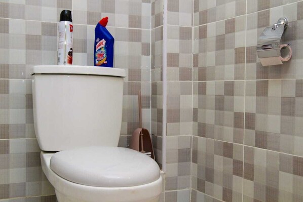 A bathroom with a toilet, a roll of toilet paper, and a bottle of Harpic toilet cleaner. - Stay.Plus Milimani Luxe Apartment (Kisumu)