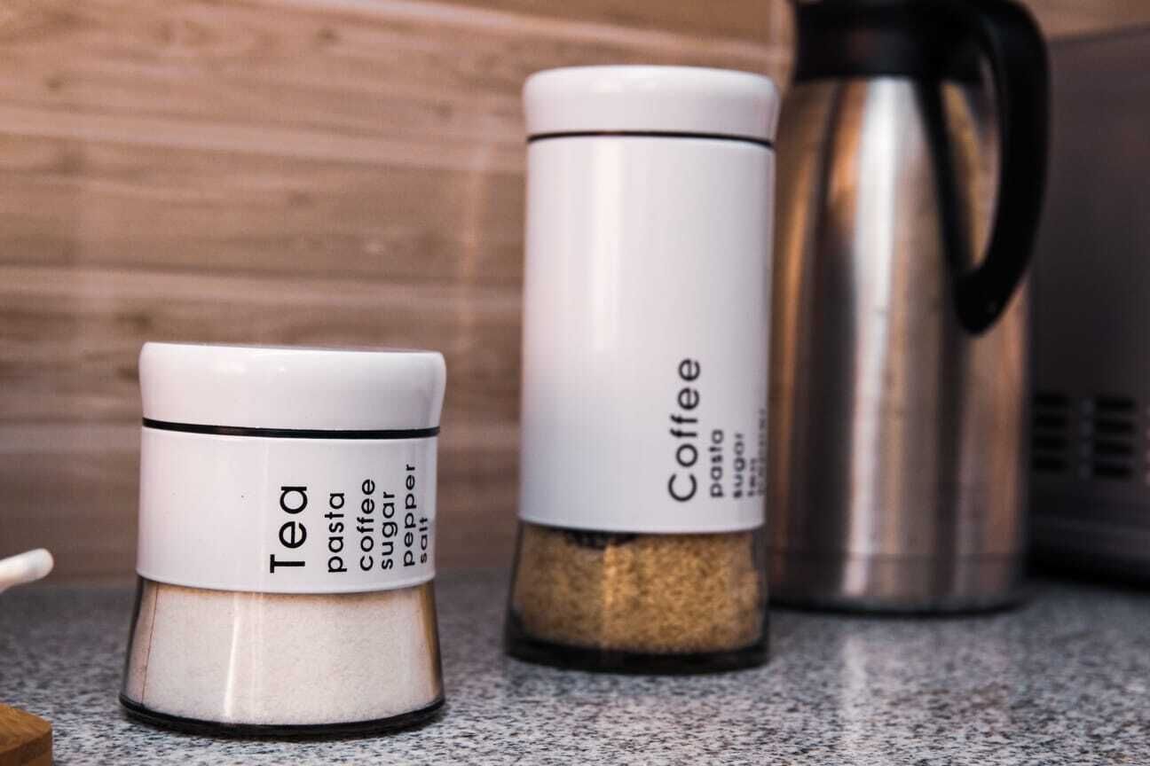 Two containers labeled 'Tea' and 'Coffee' with a coffee maker in the background.
