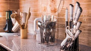 A kitchen counter with various utensils and cookware, including knives, spoons, and a grater. - Stay.Plus Milimani Luxe Apartment (Kisumu)