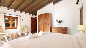 Un dormitorio con una cama grande, un armario de madera y un ventanal con cortinas.
