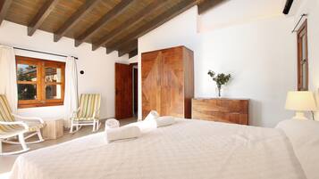 A bedroom with a large bed, wooden wardrobe, and a window with curtains.