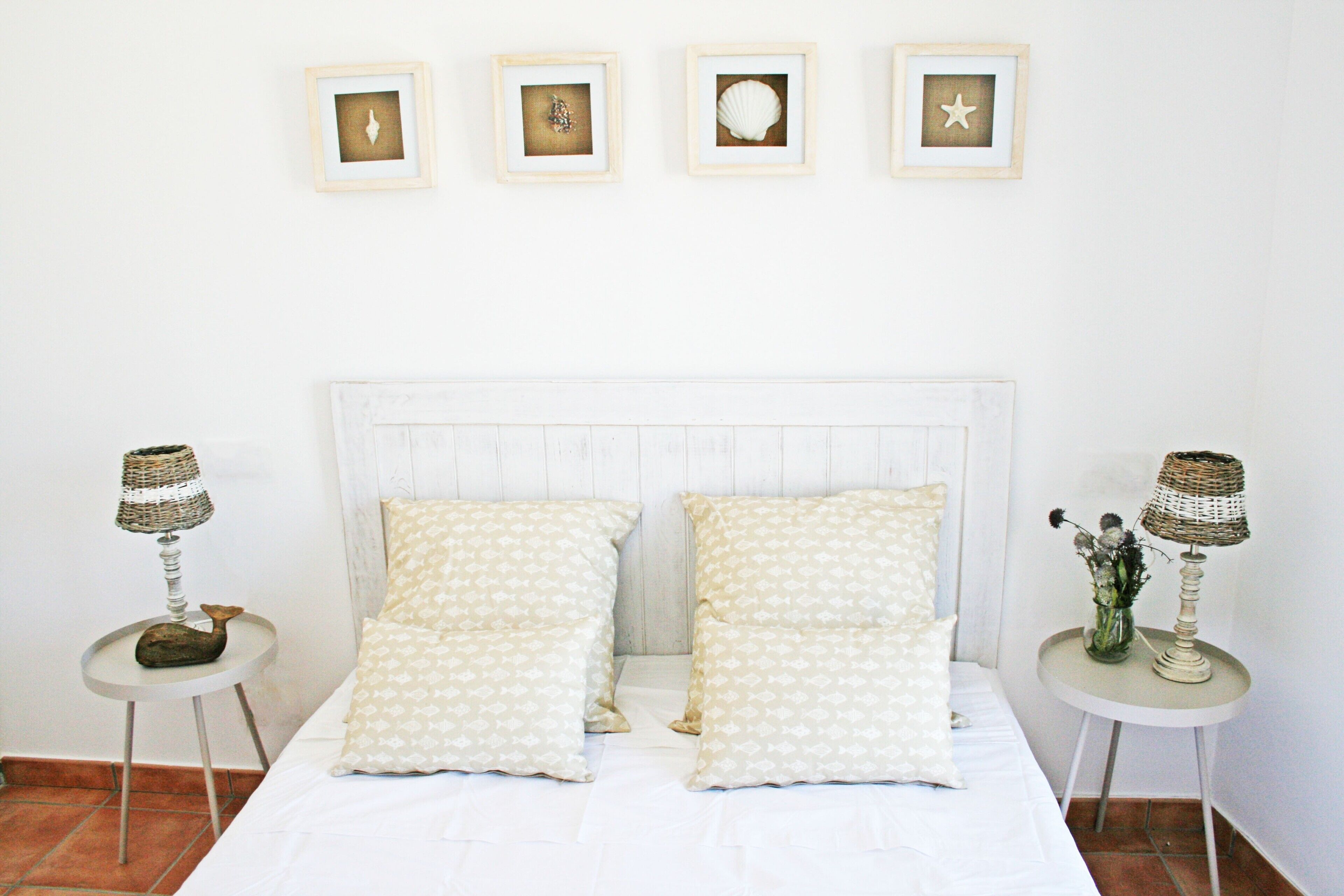 A bed with two pillows, two nightstands with lamps, and four framed pictures on the wall.